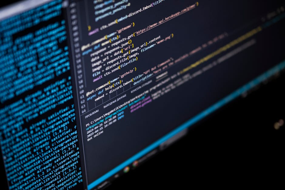 Close-up view of a computer screen displaying lines of programming code in various colors, including blue, yellow, and white, with some lines slightly blurred for depth. The code appears to be part of