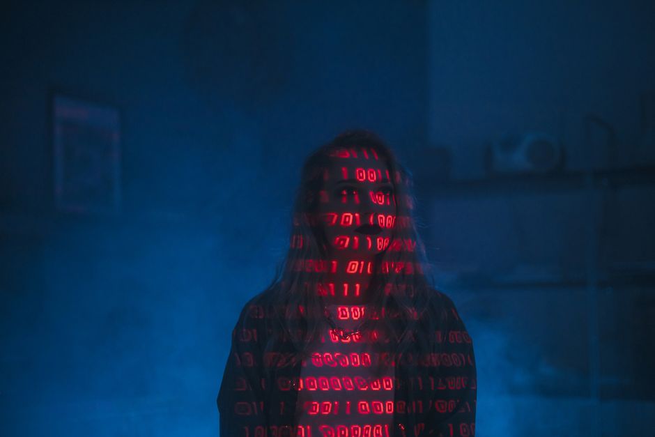 Close-up view of a computer screen displaying lines of programming code in various colors, including blue, yellow, and white, with some lines slightly blurred for depth. The code appears to be part of